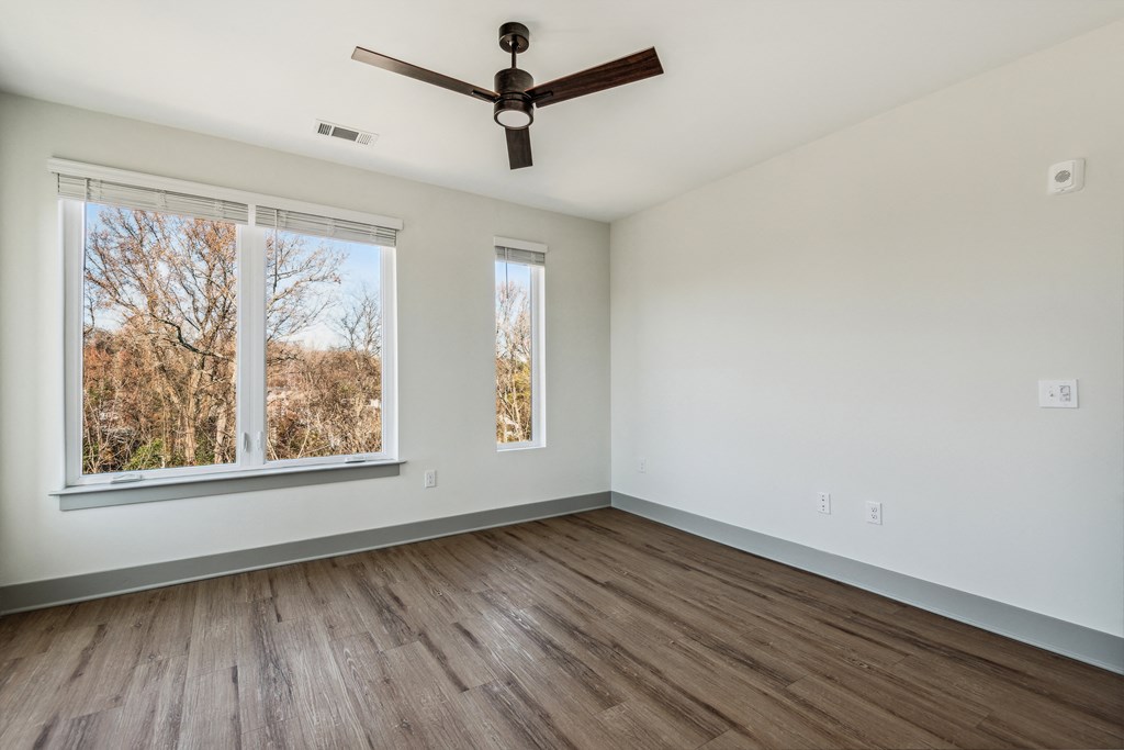 an empty living room with wood floors and a ceiling fan