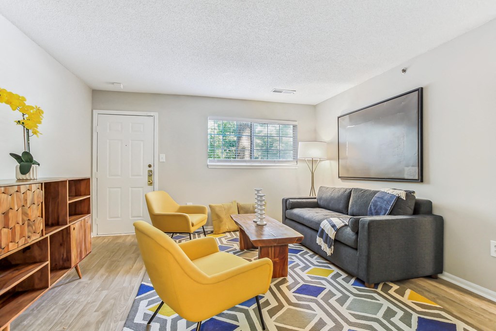 a living room with a gray couch and yellow chairs