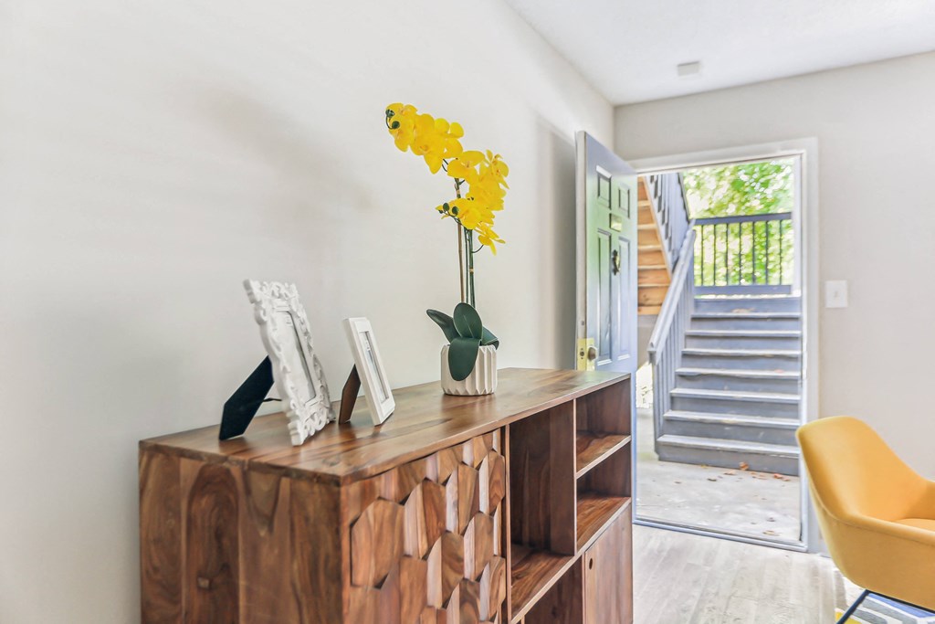 a living room with a wooden dresser and a yellow flower in a vase