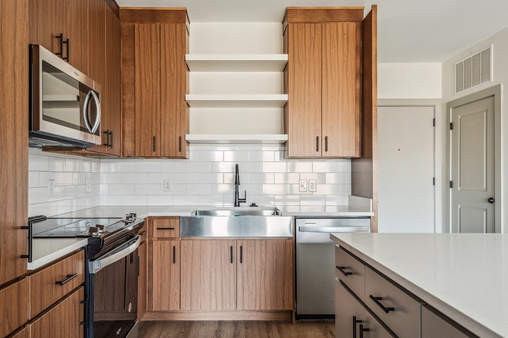 a kitchen with wooden cabinets and white countertops and a stainless steel sink