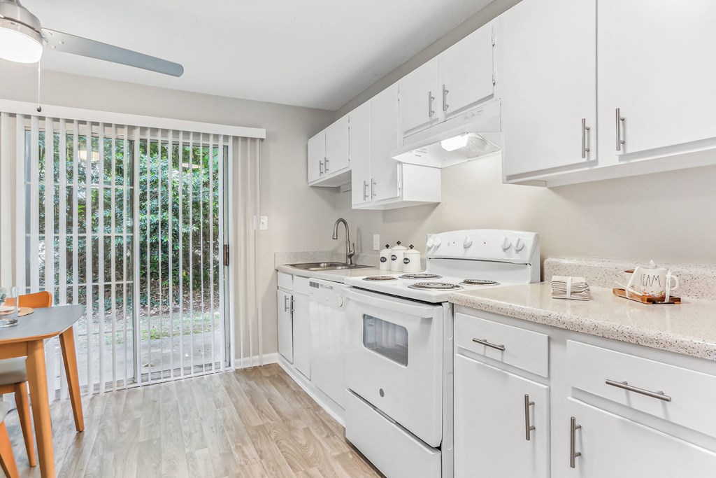a classic unit kitchen with white cabinets and a sliding glass door