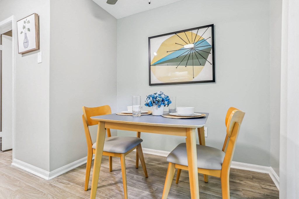 a dining area with a table and chairs and a painting on the wall