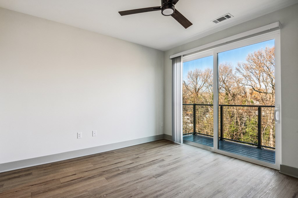 an empty living room with a large window and a balcony