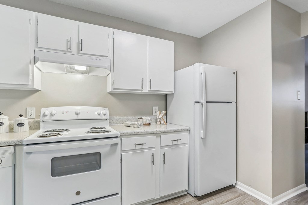 a classic unit kitchen with white appliances and white cabinets