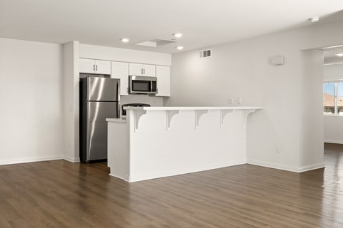 A kitchen with a refrigerator, microwave, and stove top oven.