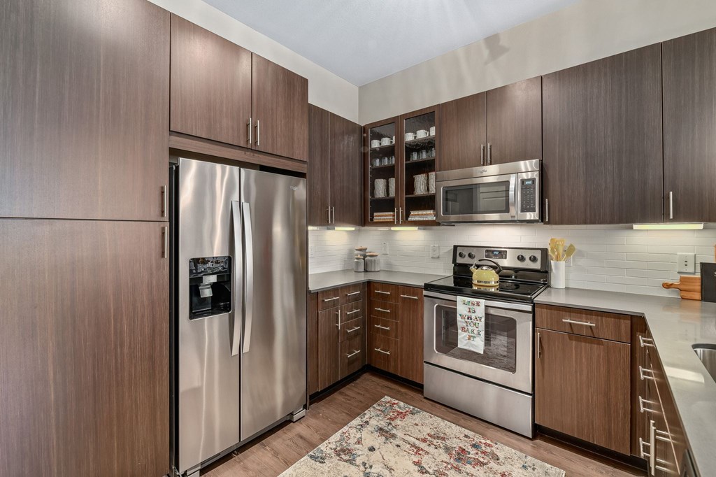 A kitchen with a refrigerator, oven, and microwave.