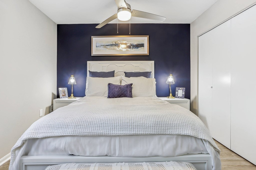 a bedroom with a blue accent wall and a white bed