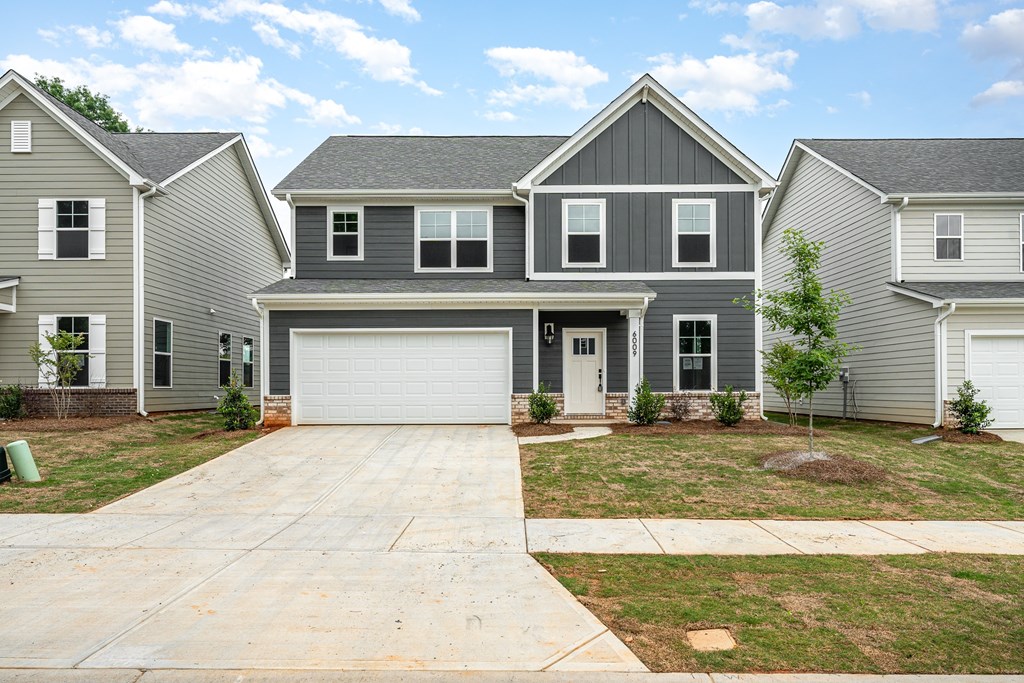 A grey house with a white garage door in front.