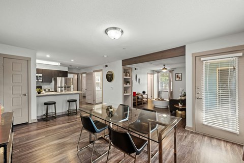 A modern kitchen with a glass table and bar stools.