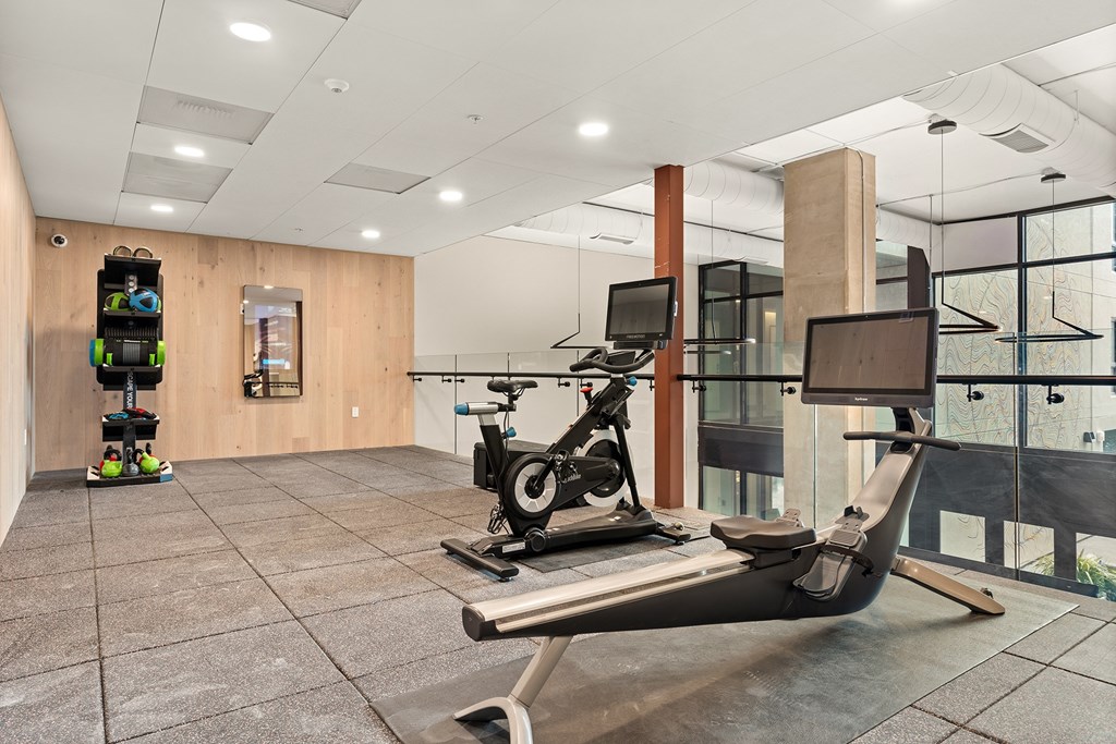 A treadmill is in the middle of a room with a wooden wall and a window.