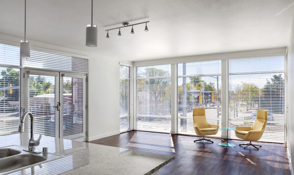 a living room with sliding glass doors and a kitchen with a sink and chairs