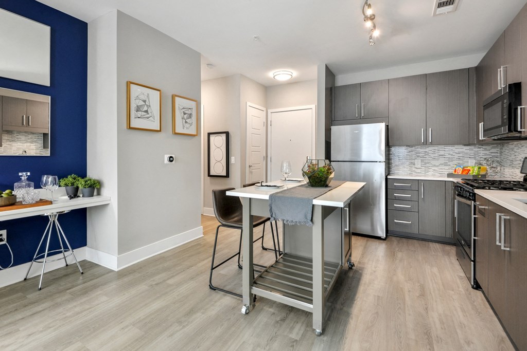 an open kitchen and dining area with stainless steel appliances and a table with chairs