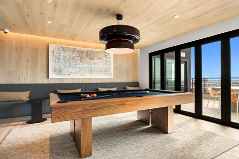 A pool table is in the middle of a room with a view of the ocean.