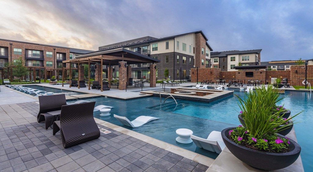 a swimming pool with chairs and a building in the background