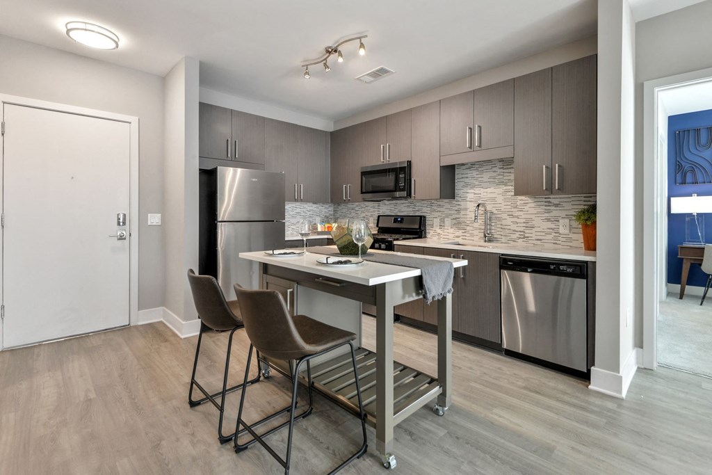 a kitchen with stainless steel appliances and a bar with three chairs