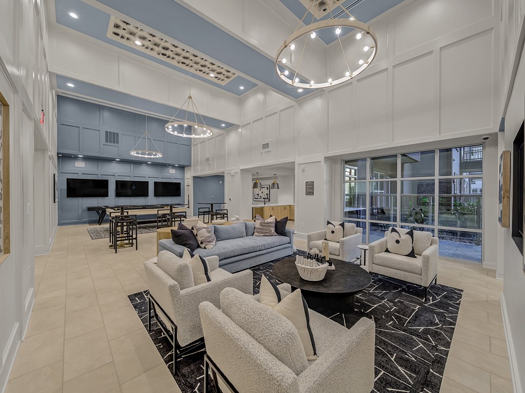 A spacious living room with a black coffee table and grey chairs.