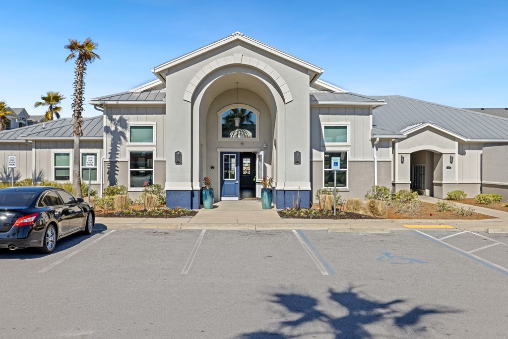 A black car is parked in front of a building with a palm tree.