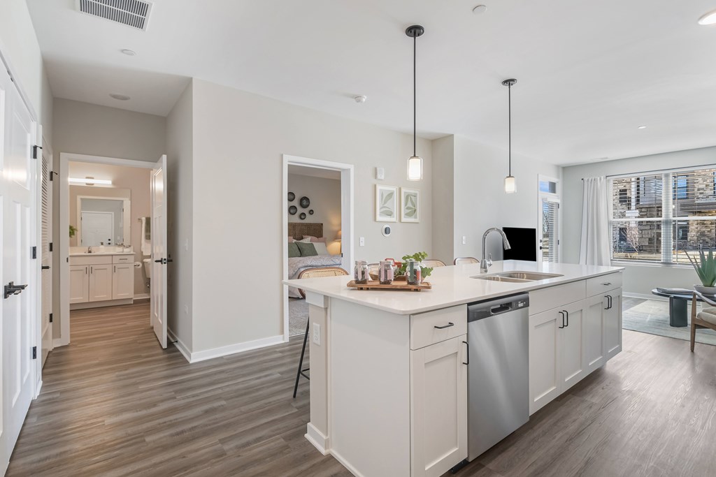 A modern kitchen with white cabinets and a wooden floor.