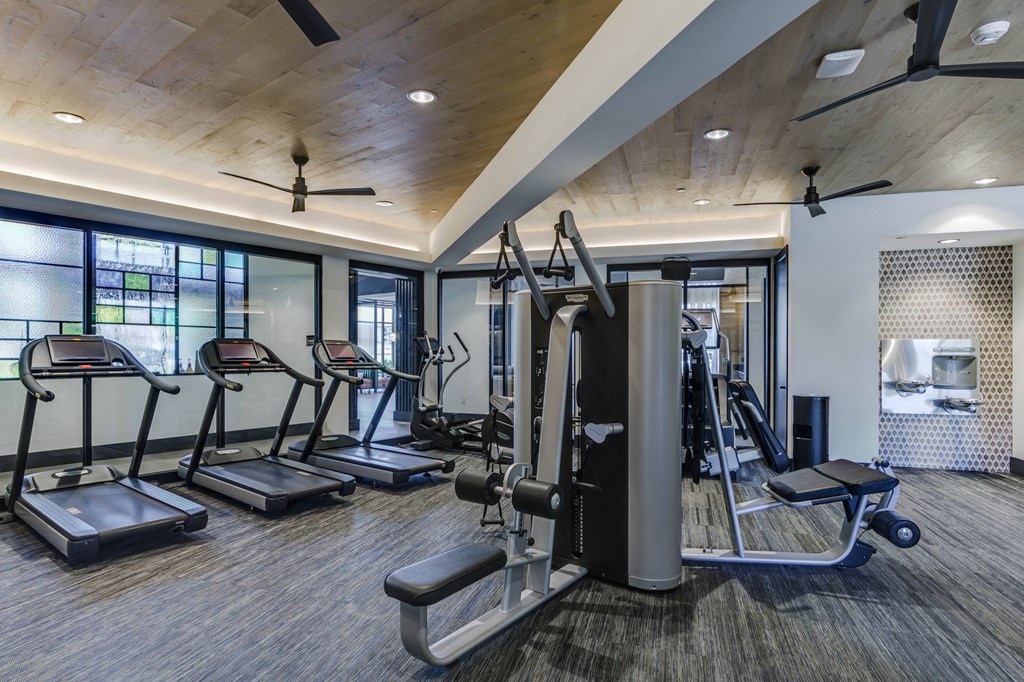 a gym with treadmills and other exercise equipment in a building with windows