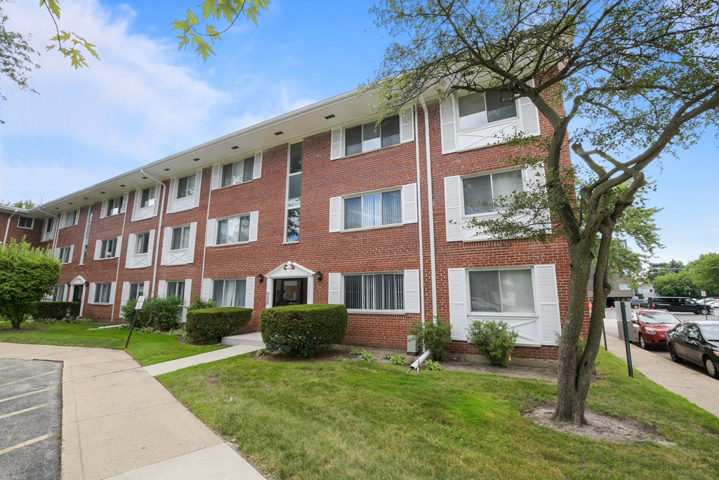 a brick apartment building with a sidewalk in front of it