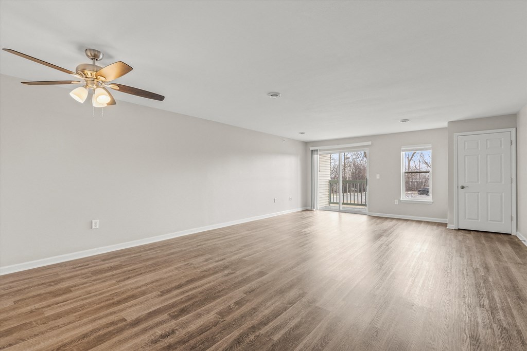 an empty living room with white walls and a ceiling fan