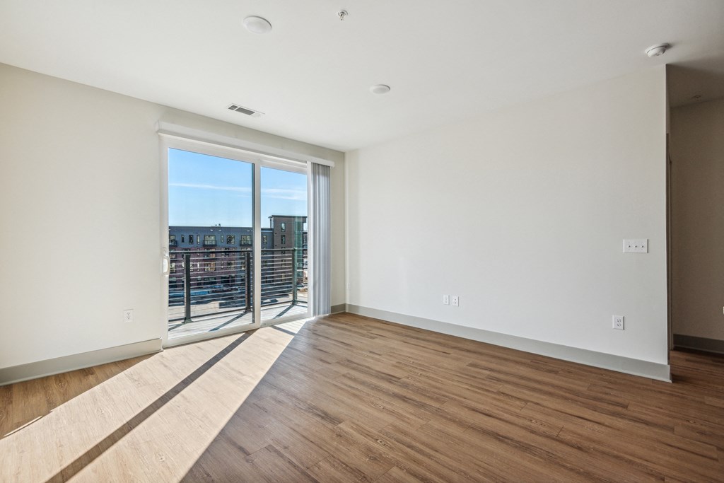 an empty living room with wood flooring and a balcony