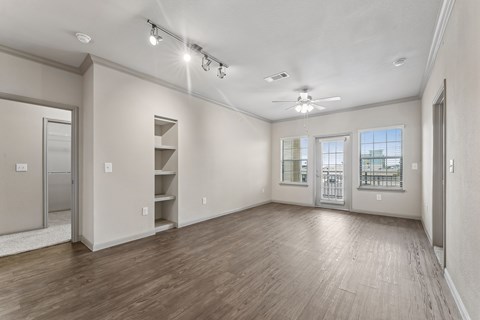 A spacious room with wooden floors and a ceiling fan.