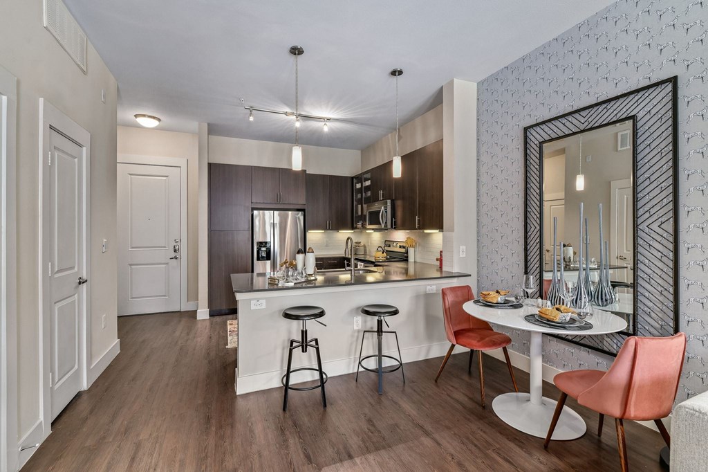 A kitchen with a bar stool and a dining table.