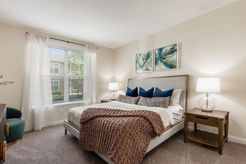 A bedroom with a large bed and a window with curtains.