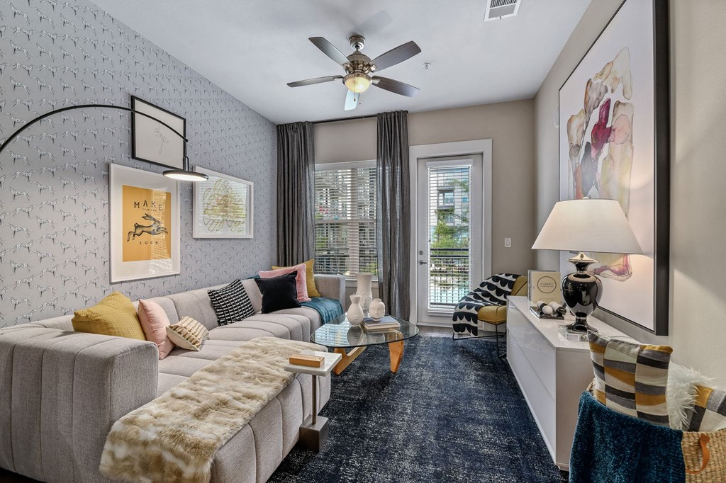 A living room with a grey couch and a ceiling fan.