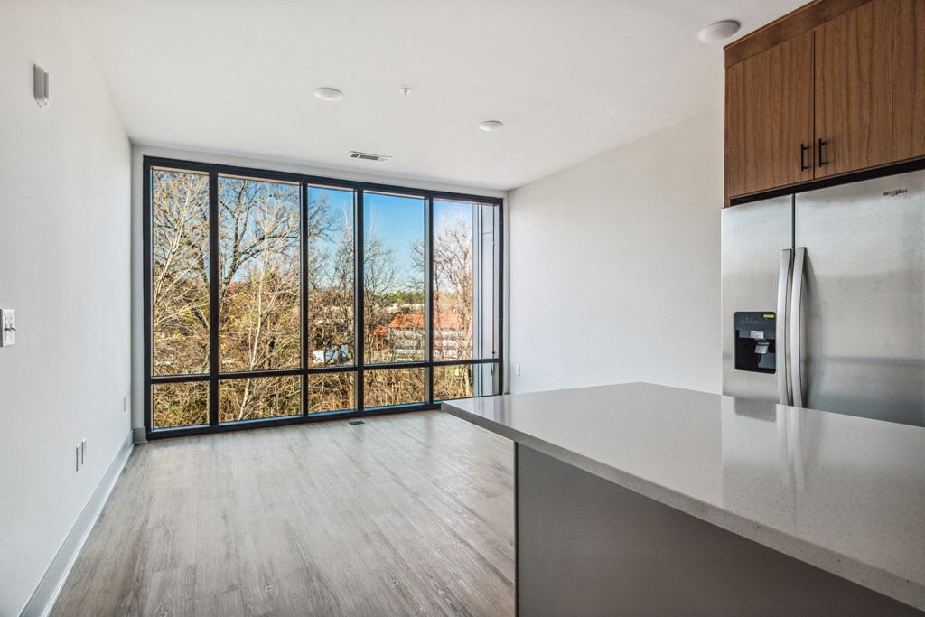 a kitchen with white walls and a large window with trees