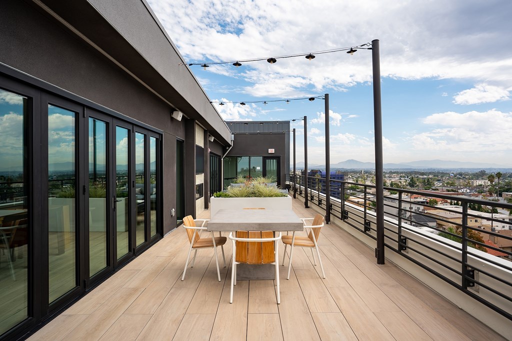 A balcony with a table and chairs overlooking a cityscape.