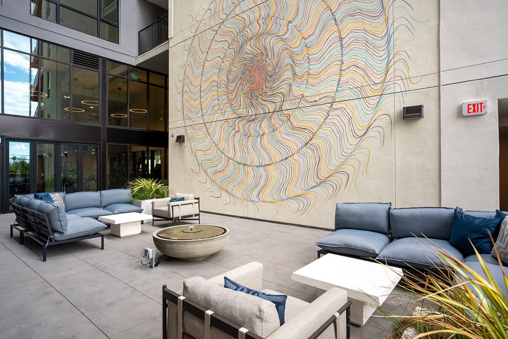 A large artwork on a wall in a modern outdoor seating area.