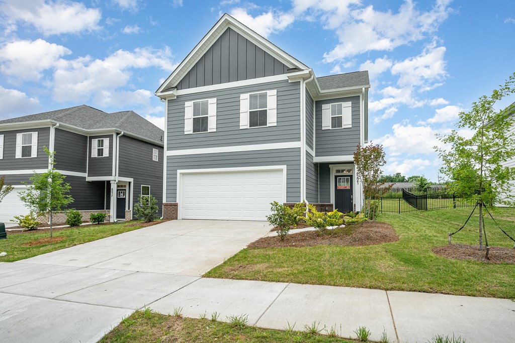 A grey house with a white garage door and a black fence.
