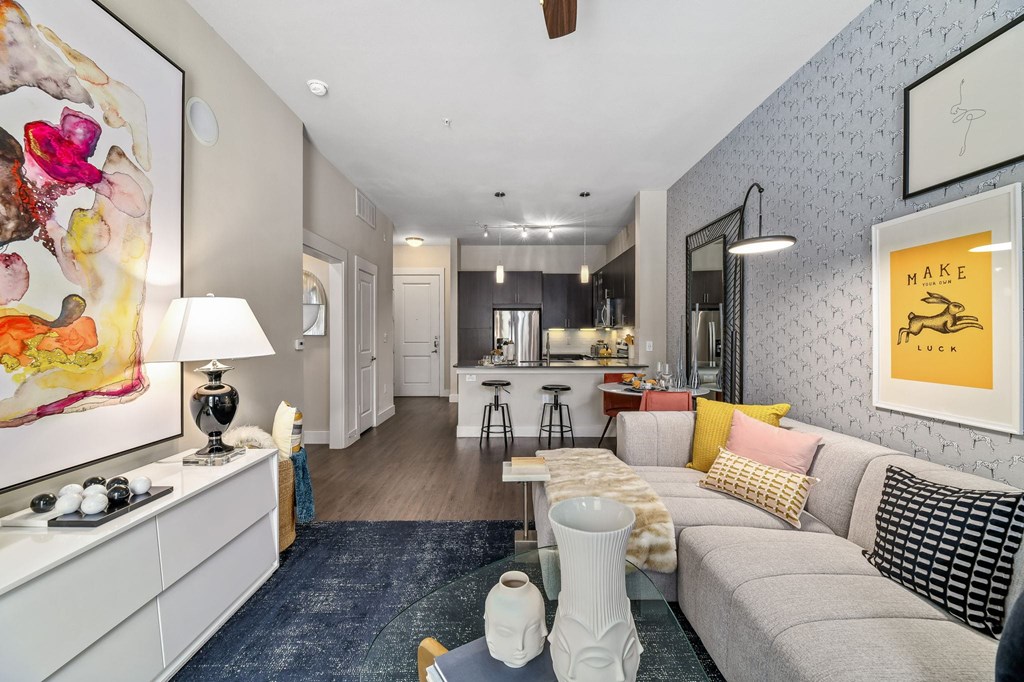 A living room with a grey couch and a painting on the wall.