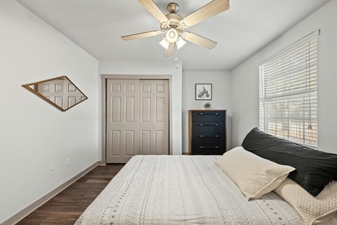 A bedroom with a bed, dresser, and ceiling fan.