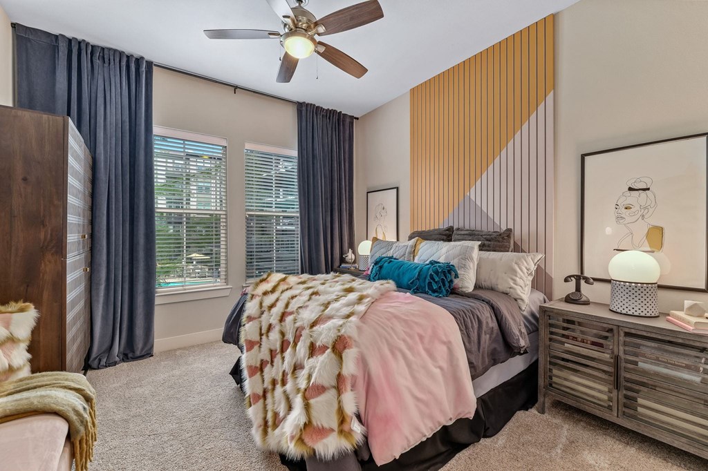 A bedroom with a bed, a ceiling fan, and a window with curtains.