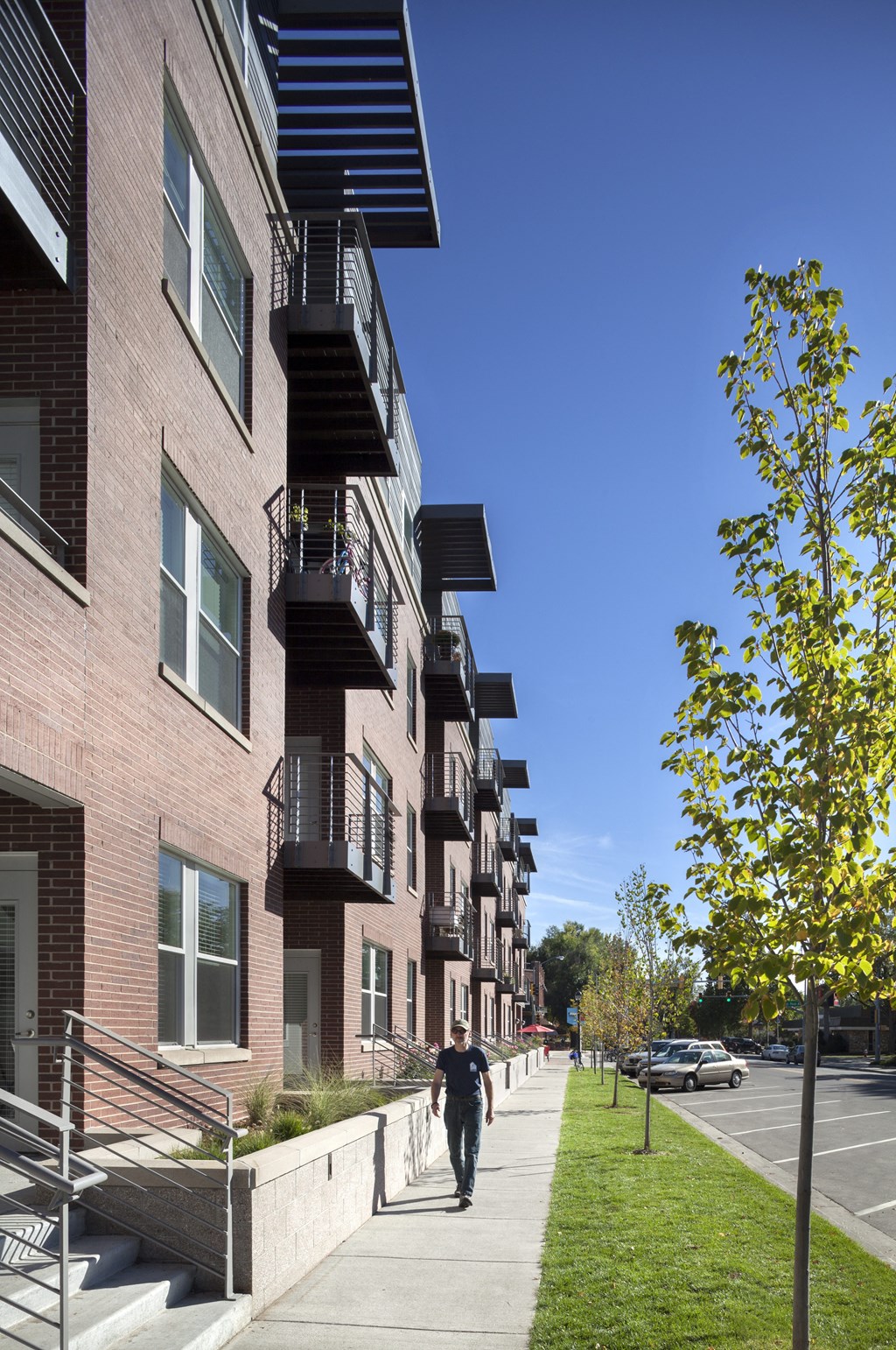 a man walking down a sidewalk in front of a row of apartment buildings