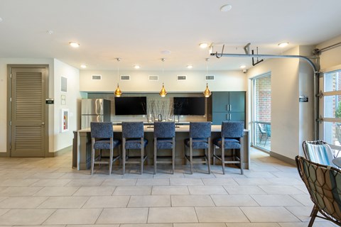 a large kitchen with a large island with blue chairs and a bar with chairs