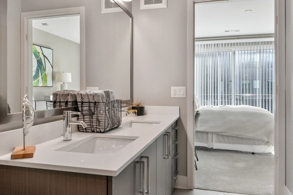 a bathroom with a sink and a mirror and a bedroom