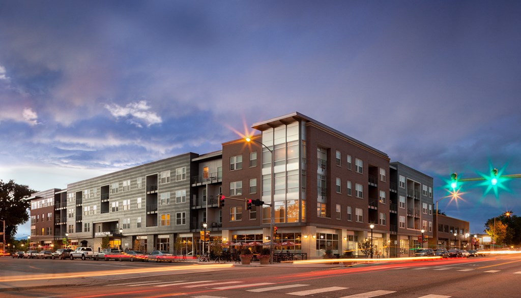 a large apartment building at night with traffic lights