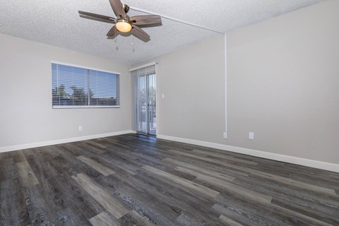 an empty living room with a ceiling fan and a window