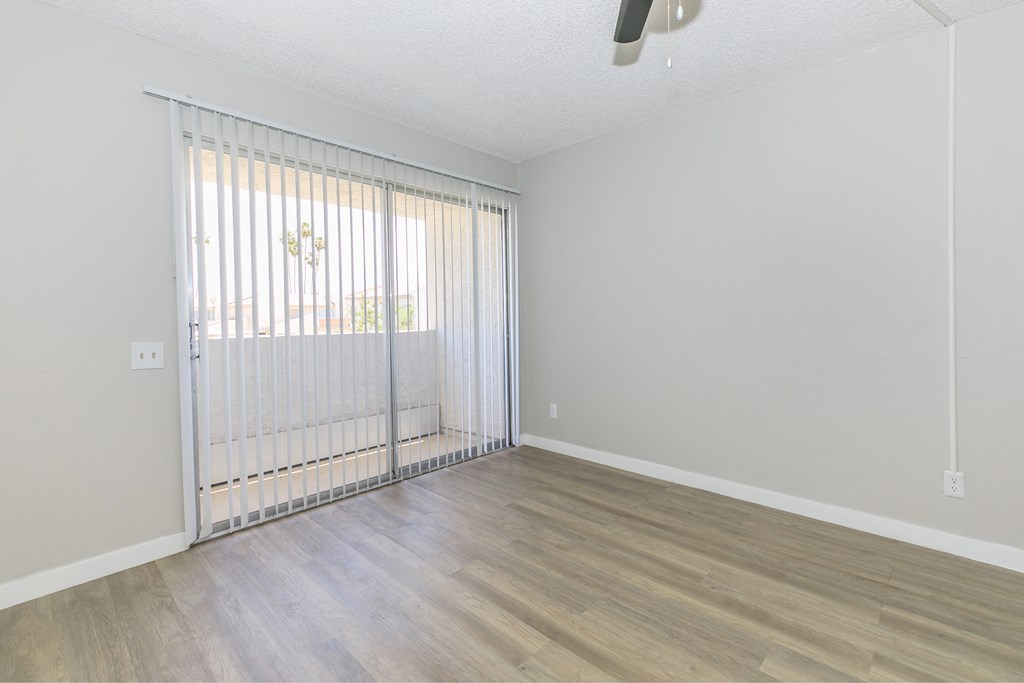 a bedroom with hardwood flooring and a sliding glass door to a balcony