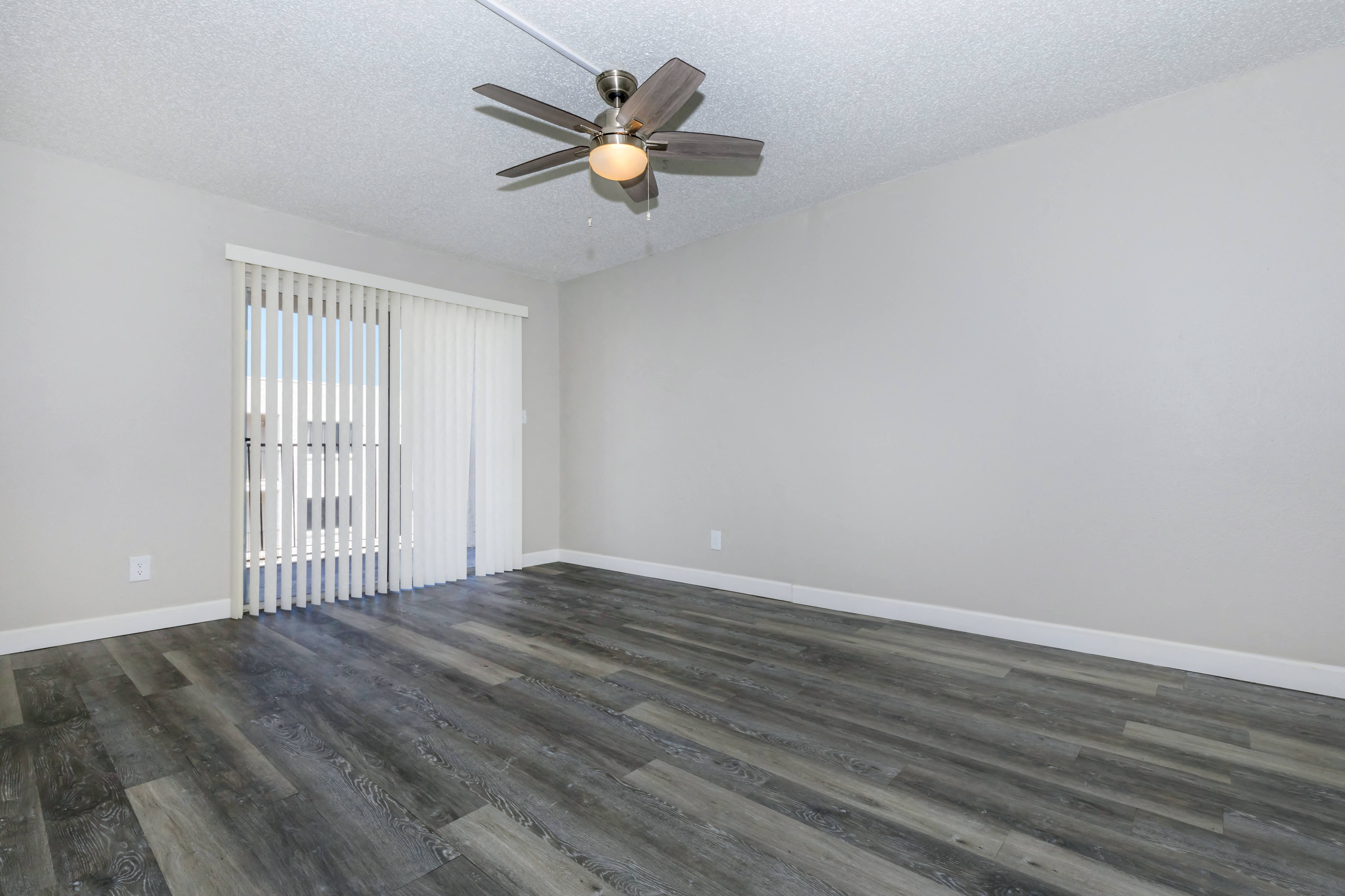 an empty living room with wood flooring and a ceiling fan
