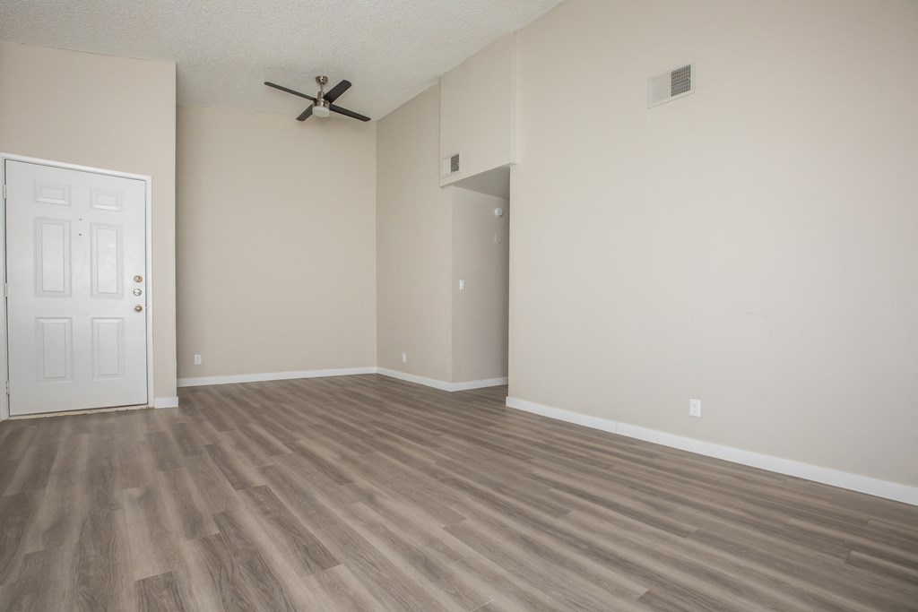 an empty living room with a ceiling fan