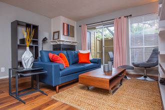 a living room with a blue couch and orange pillows