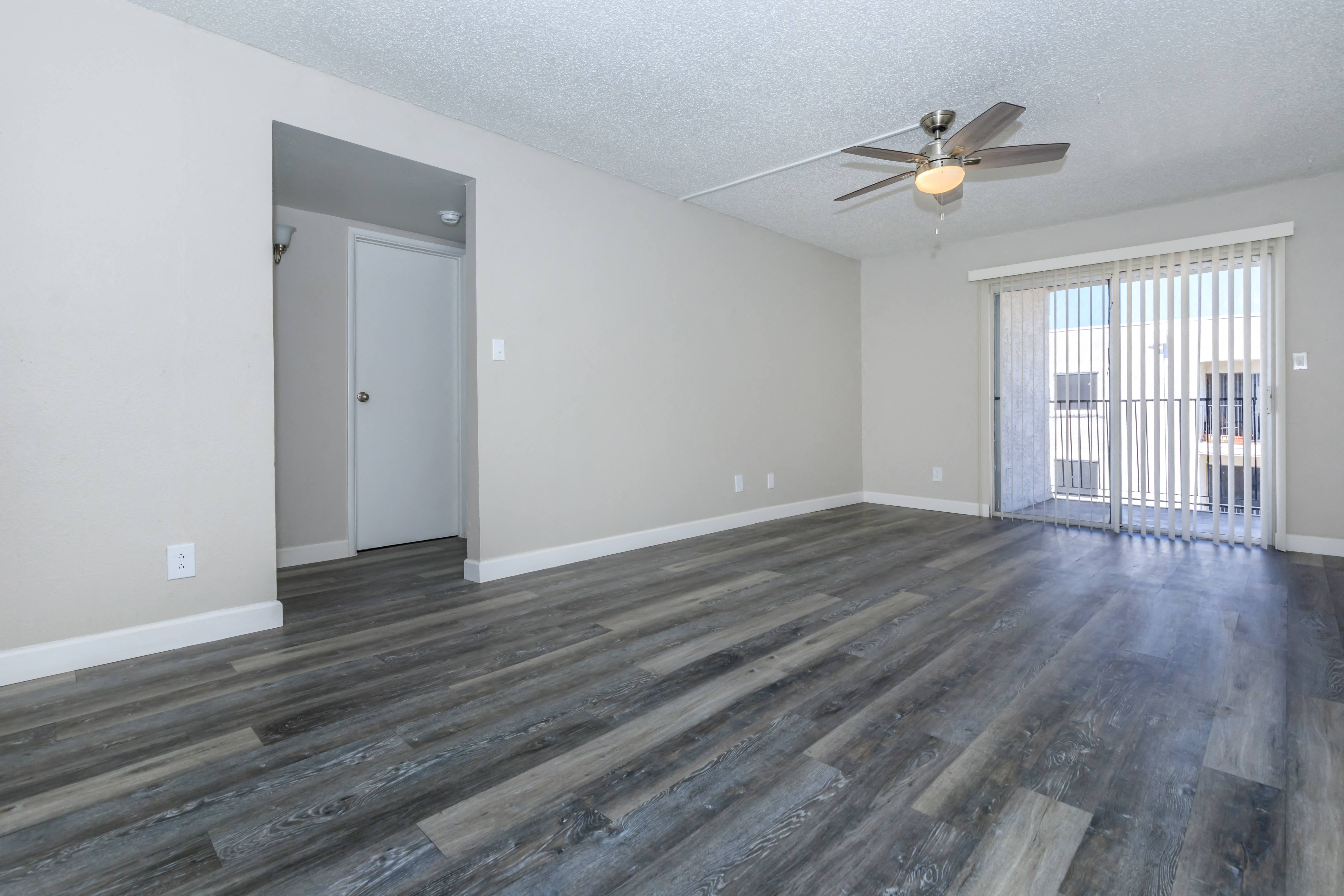 an empty living room with wood flooring and a ceiling fan