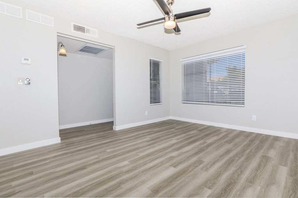 an empty living room with a ceiling fan and a window