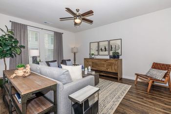 A living room with a grey couch, a wooden table, a white chair, and a brown armchair.