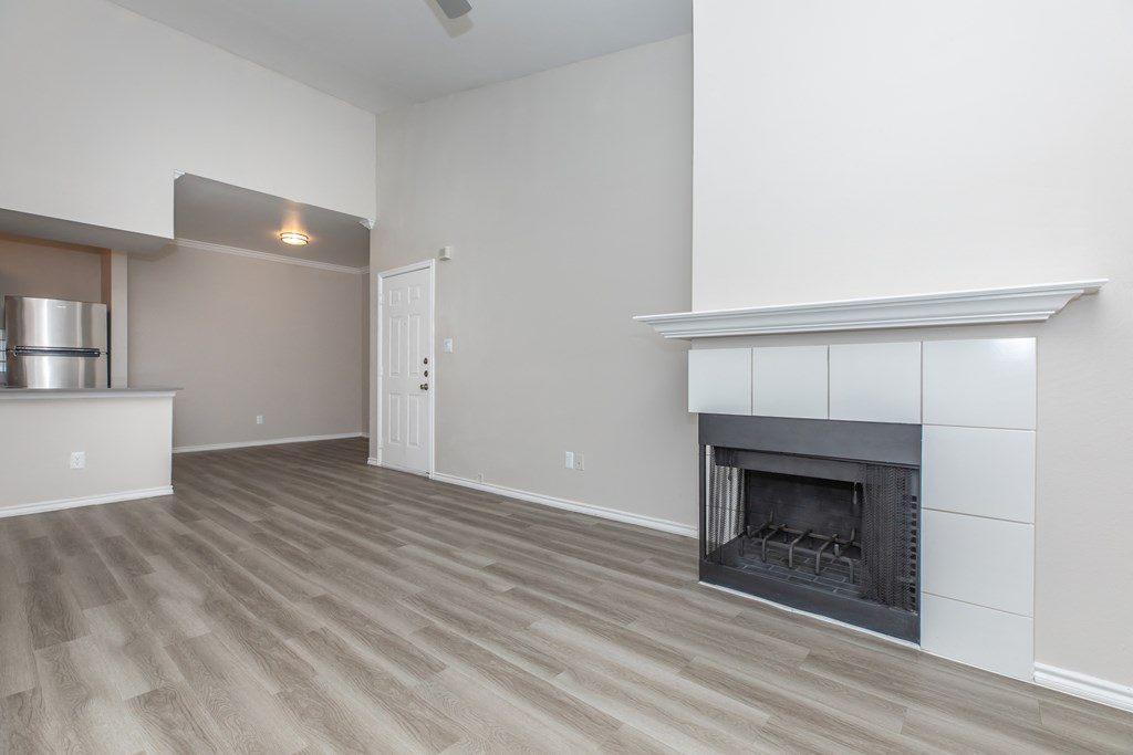 a living room with a fireplace and a kitchen in the background